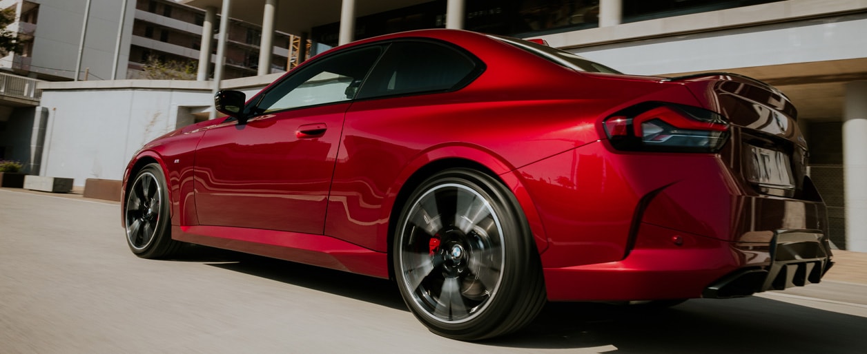 The rear view of the 2025 BMW M240i xDrive showcases a sporty and aggressive design with sharp, angular lines.
