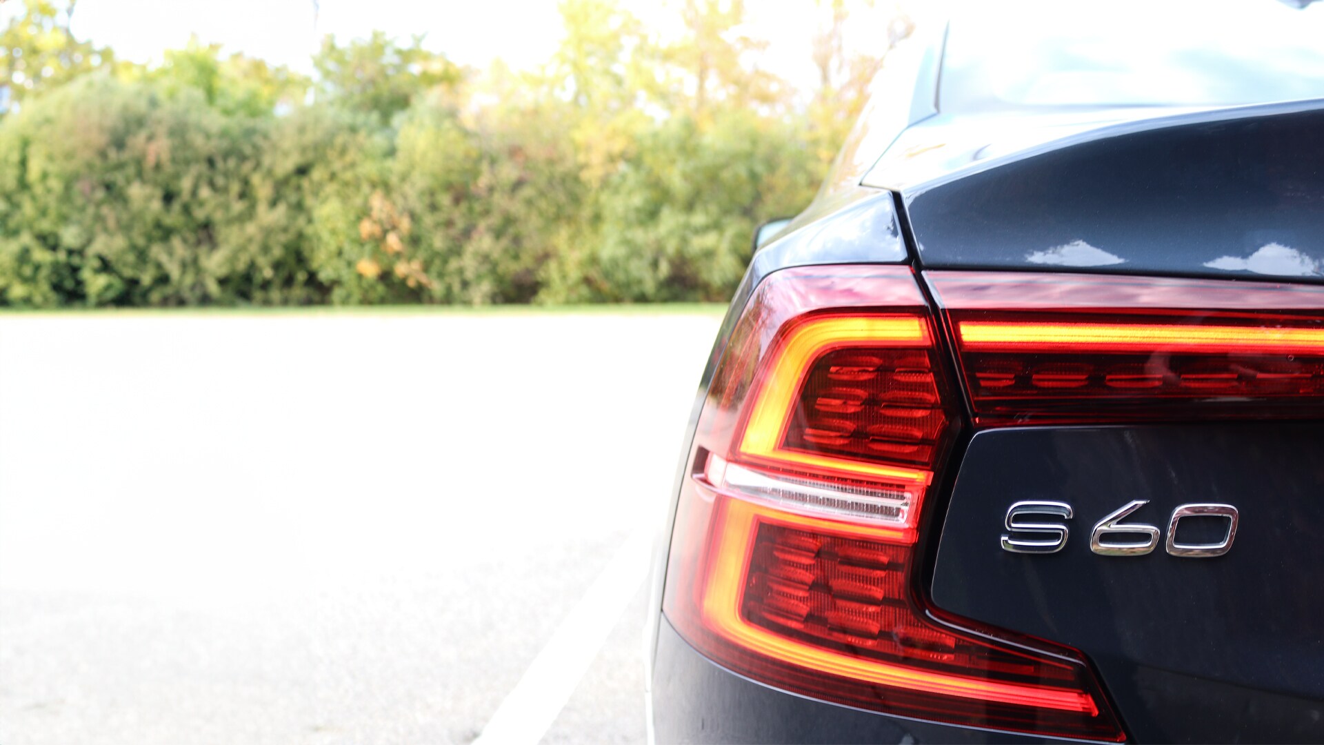 2025 Volvo S60 rear view showcasing its sculpted tailgate, LED taillights, and dual chrome exhaust outlets.
