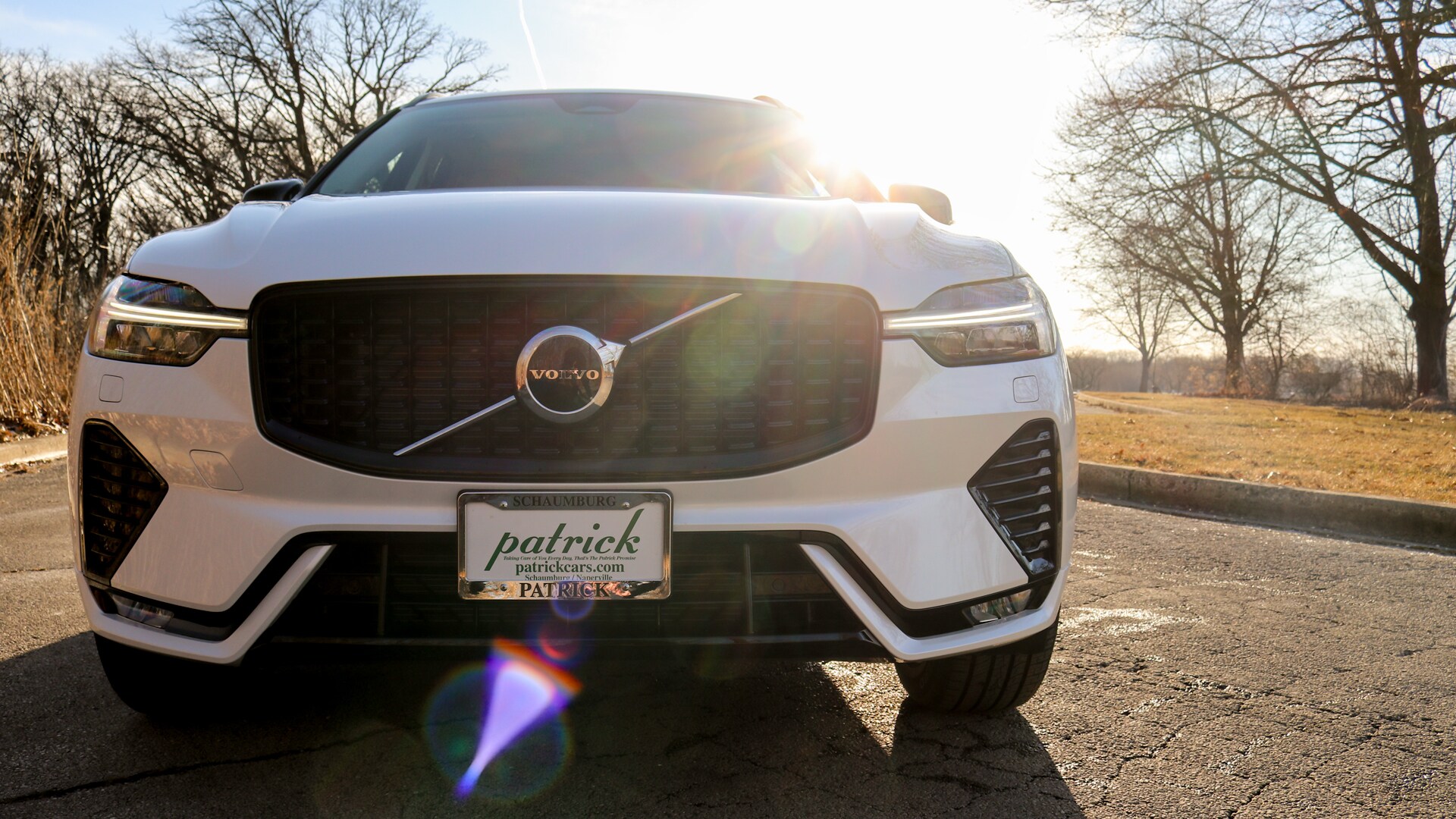 2025 Volvo XC60 Plug-In Hybrid shown in a scenic outdoor setting, highlighting its elegant exterior design, Thor's Hammer LED headlights, and charging port.
