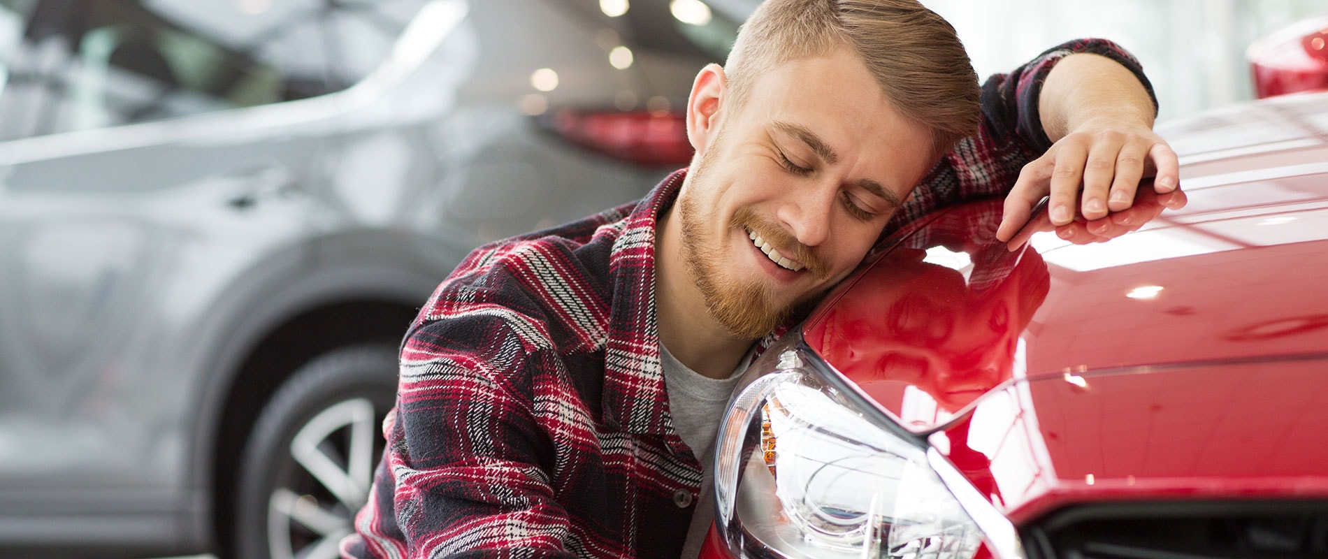 Man happily hugging the hood of his new vehicle