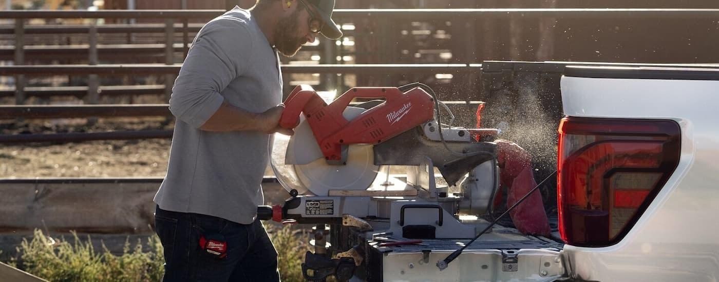 A man working on the tailgate of a white 2025 Ford F-150.
