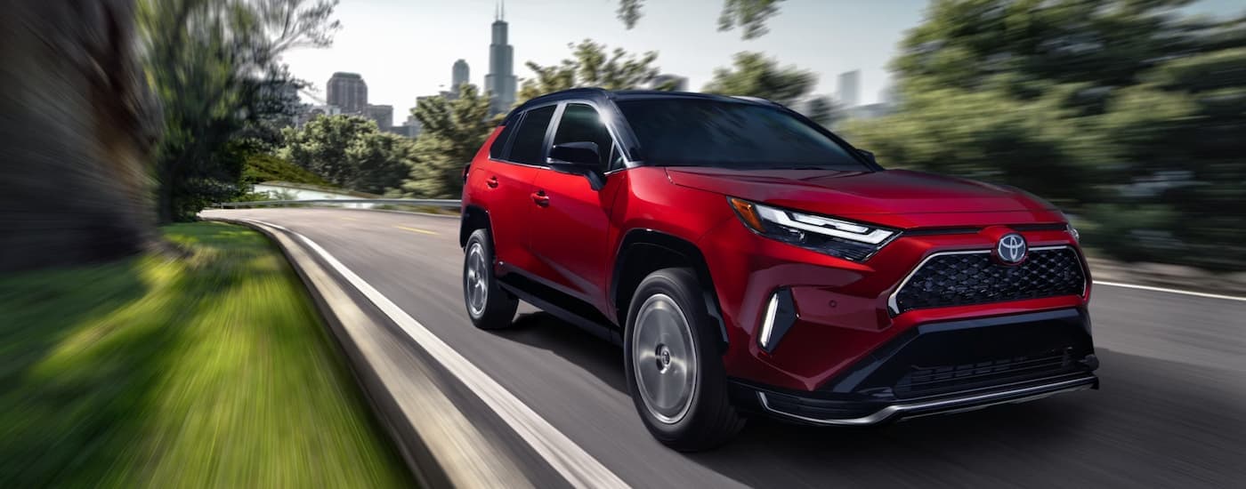 Red 2025 Toyota RAV4 for sale near Bloomington driving down a road.