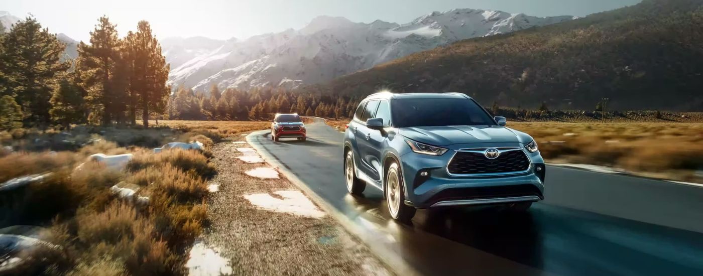 A red and a blue 2023 Toyota Hghlanders driving to see a used Toyota for sale near Moline