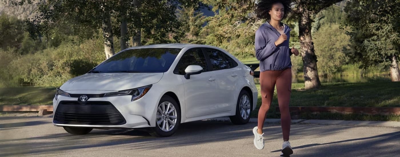 A white 2025 Toyota Corolla parked near a jogger.