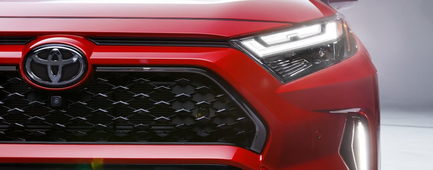 Close-up on the headlight and grille of a red 2025 Toyota RAV4.