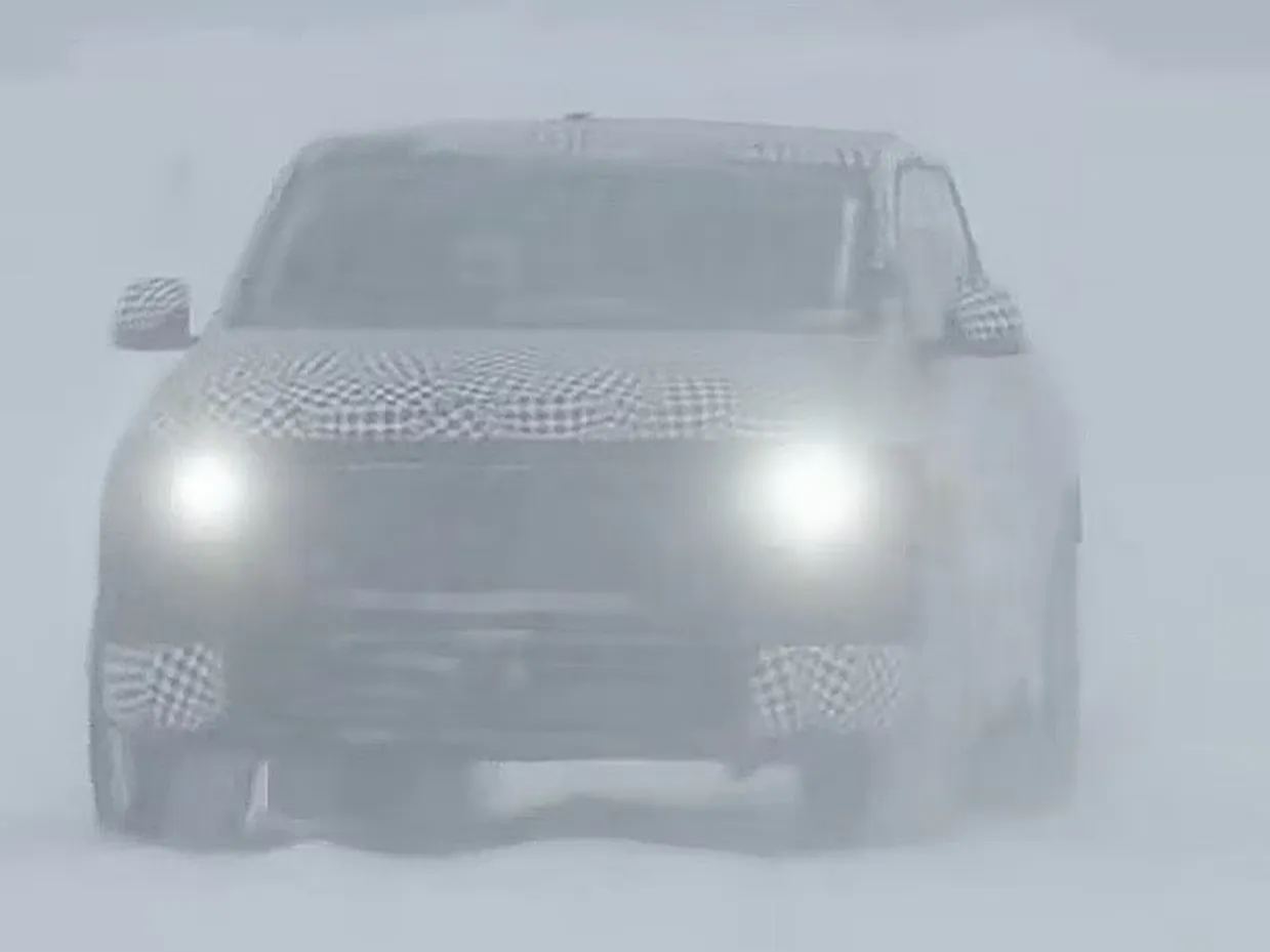 Camouflaged test vehicle driving in extreme snow conditions.