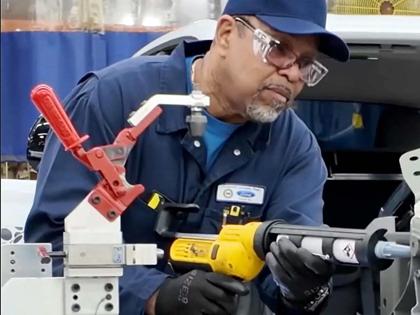 Ford technician applying sealant to a car part.