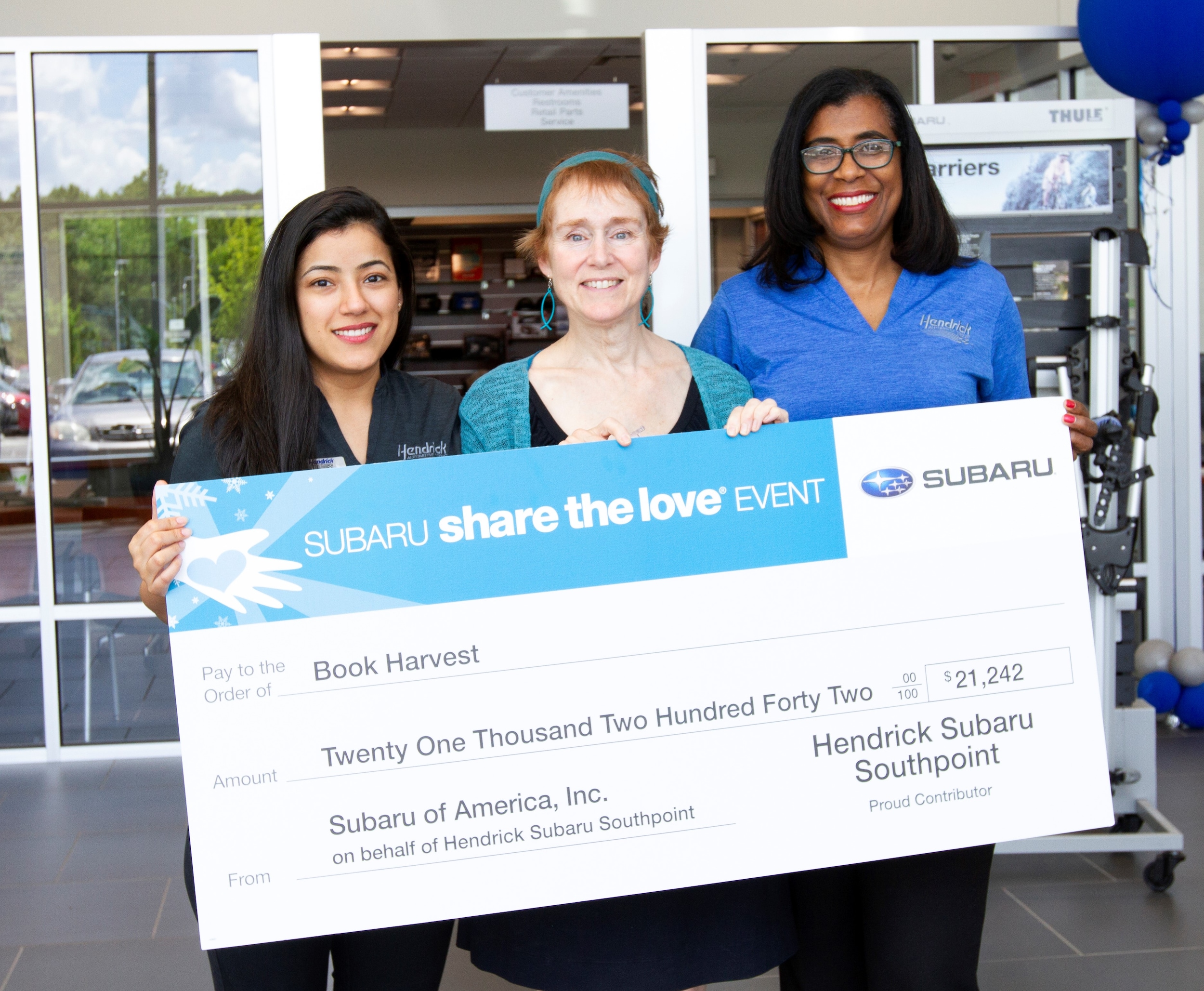 Hendrick Subaru Southpoint General Manager Anna Latta and Marketing Director Poonam Nandani present Book Harvest with Share the Love donation.