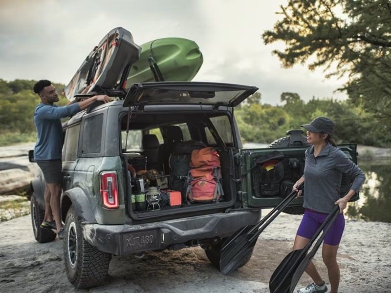 Ford Bronco Sport with the back door open and full of outdoor gear with canoes attached to the top of the SUV