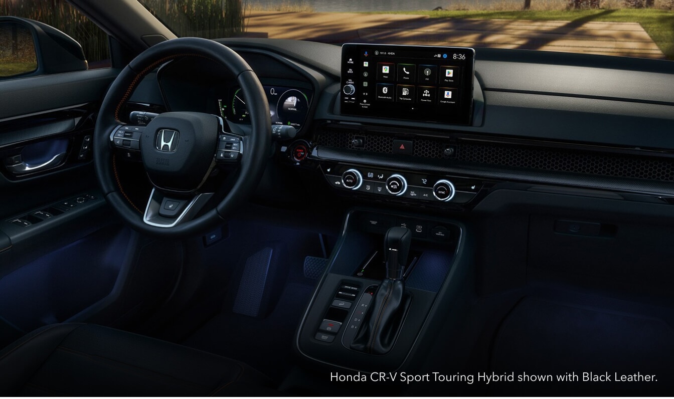 Driver-side cockpit view of a Honda CR-V Sport Touring dashboard showing the glowing center touchscreen with Black Cloth interior.