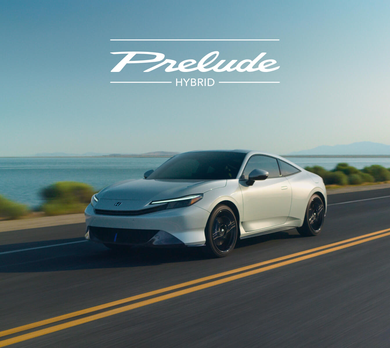 Front three-quarter view of white Honda Prelude Hybrid driving on a highway next to water.