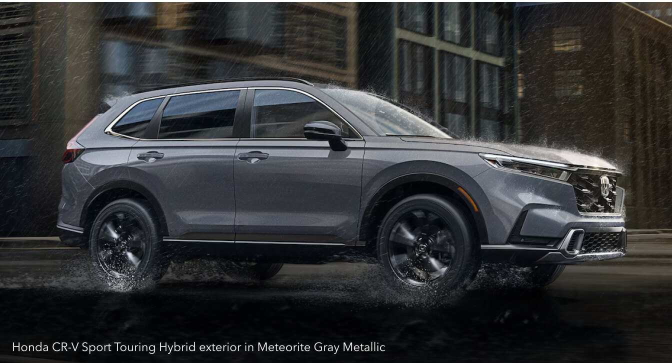Honda CR-V Sport Touring Hybrid exterior in Meteorite Gray Metallic on a rainy city street.