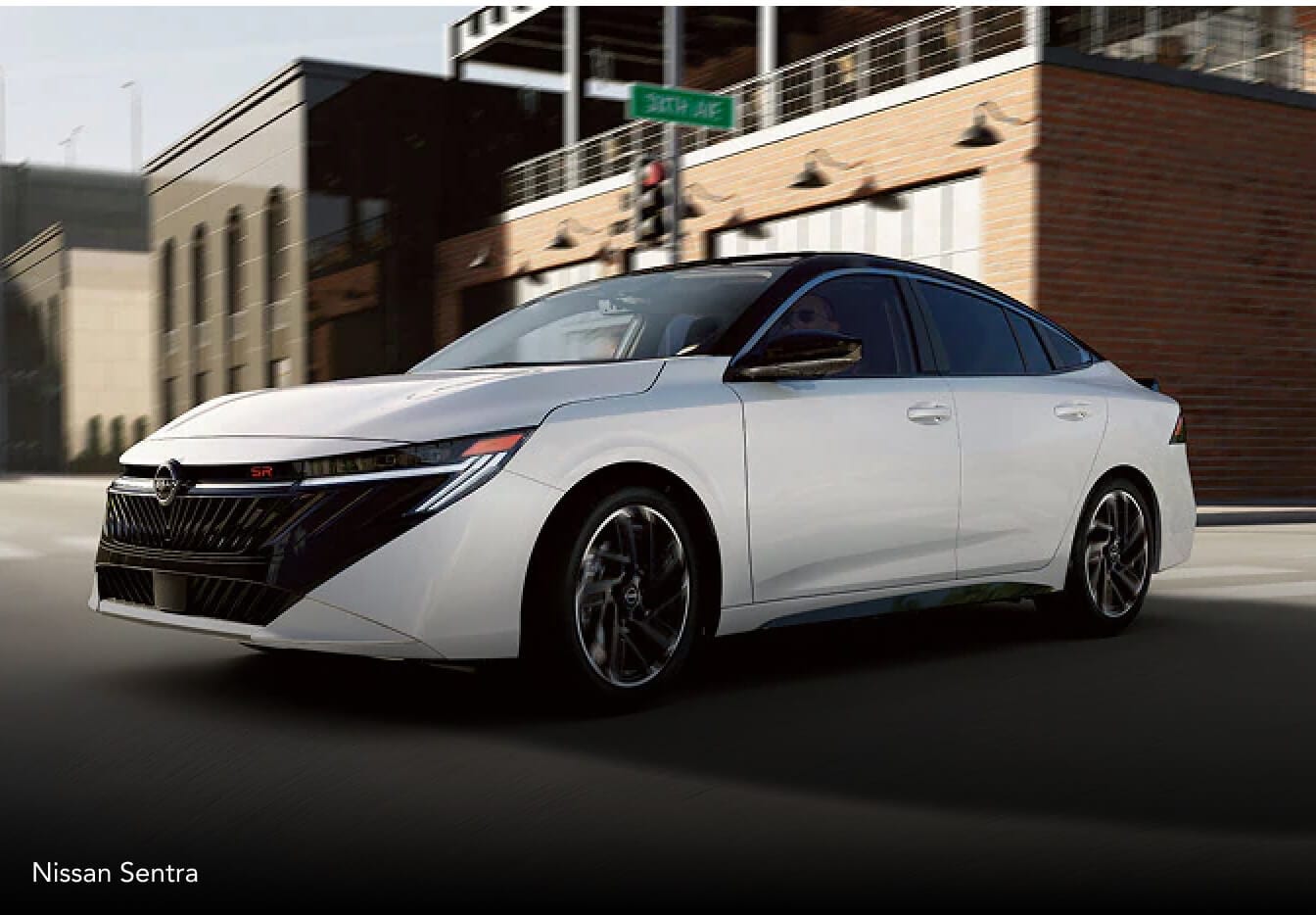 Exterior view of a white 2027 Nissan Sentra driving down a city street during the day.