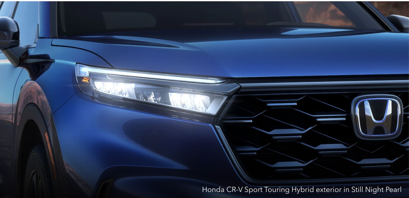 Honda CR-V Sport Touring Hybrid exterior in Still Night Pearl with LED headlights on a mountain road.