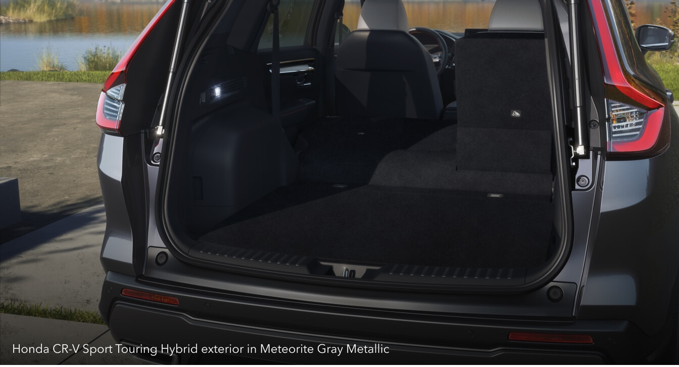Honda CR-V Sport Touring Hybrid exterior in Meteorite Gray Metallic with open trunk on a modern driveway.