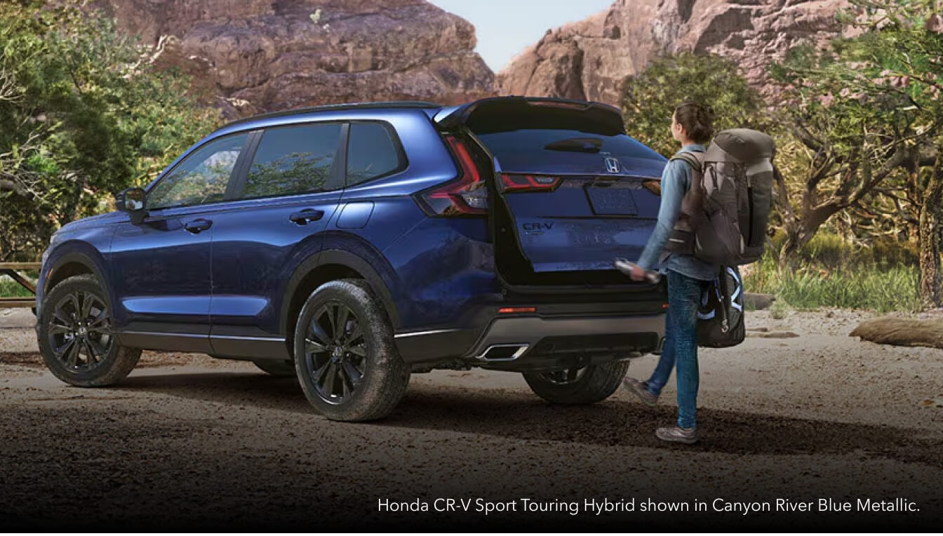 Rear three-quarter view of a Canyon River Blue Honda CR-V Sport Touring Hybrid with an open liftgate at a canyon trail.