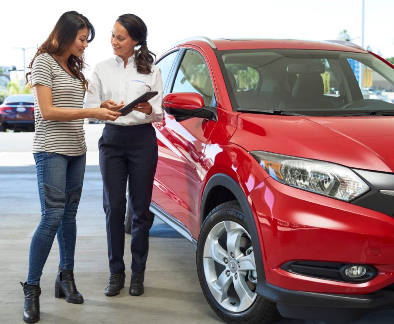 Honda service technician working on a red Honda with a customer
