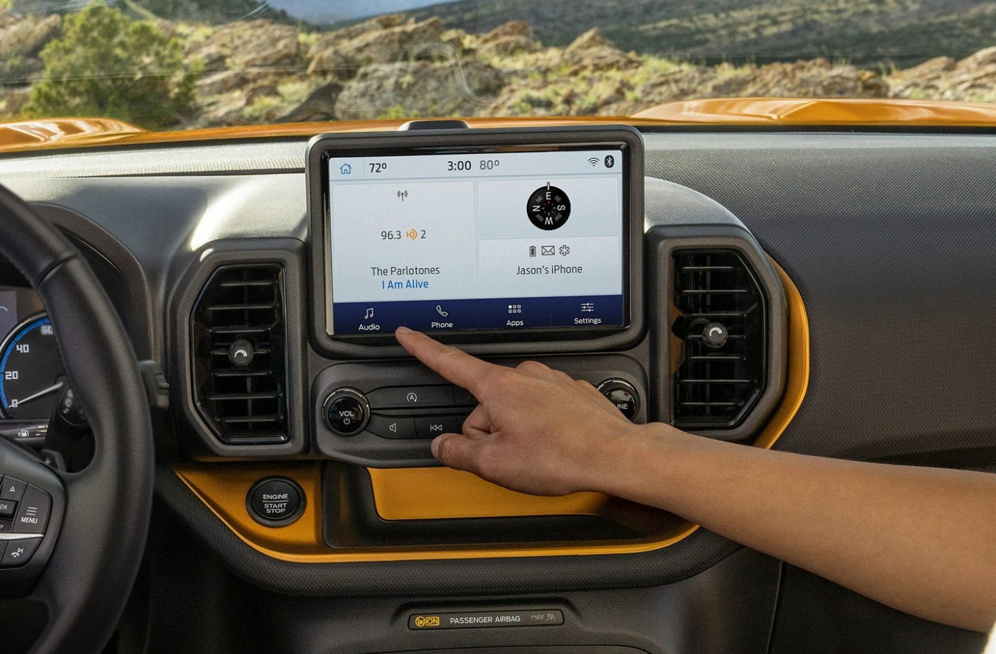 A man's hand reaches towards the infotainment system in the dash of the 2023 Ford Bronco Sport