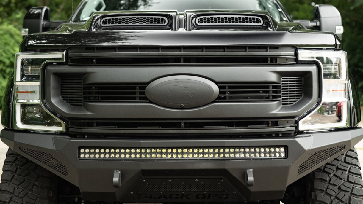 A close-up of the all black grille on the new 2022 Ford Black Ops F-150 as it sits parked outside showing the blacked out and embossed Ford logo on a black grille