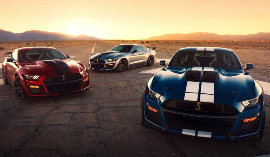 A dark red, silver, and royal blue 2020 Ford Mustangs parked on a paved road in the desert