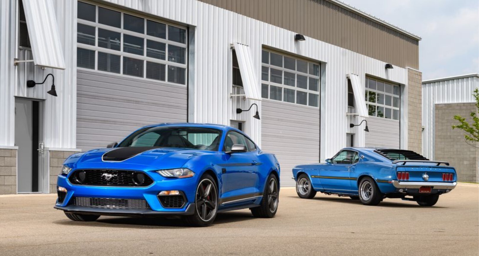 two blue Ford Mustang Mach-1s side by side, one old and one 2021 model
