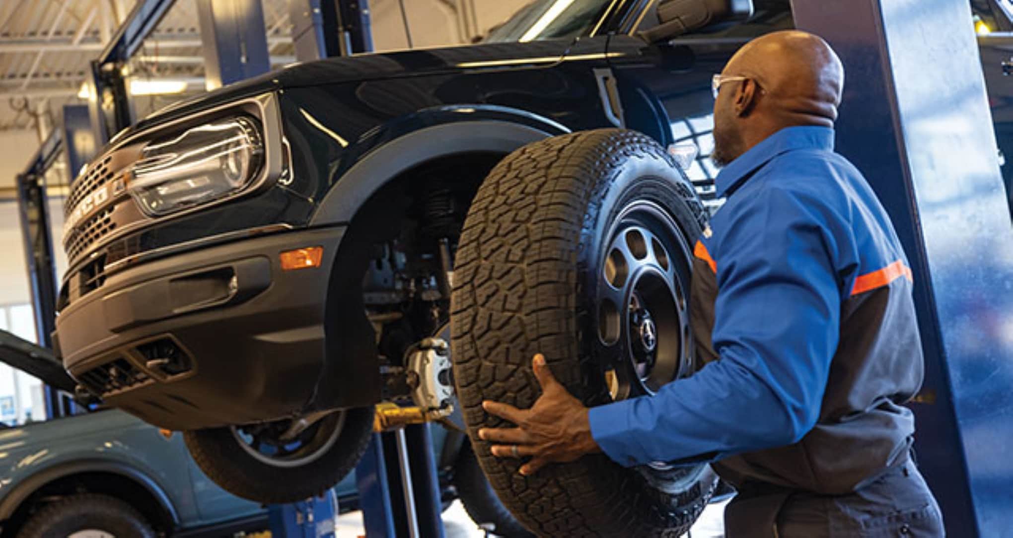 A Quick Lane technician rotating tires on a Ford Bronco Sport.