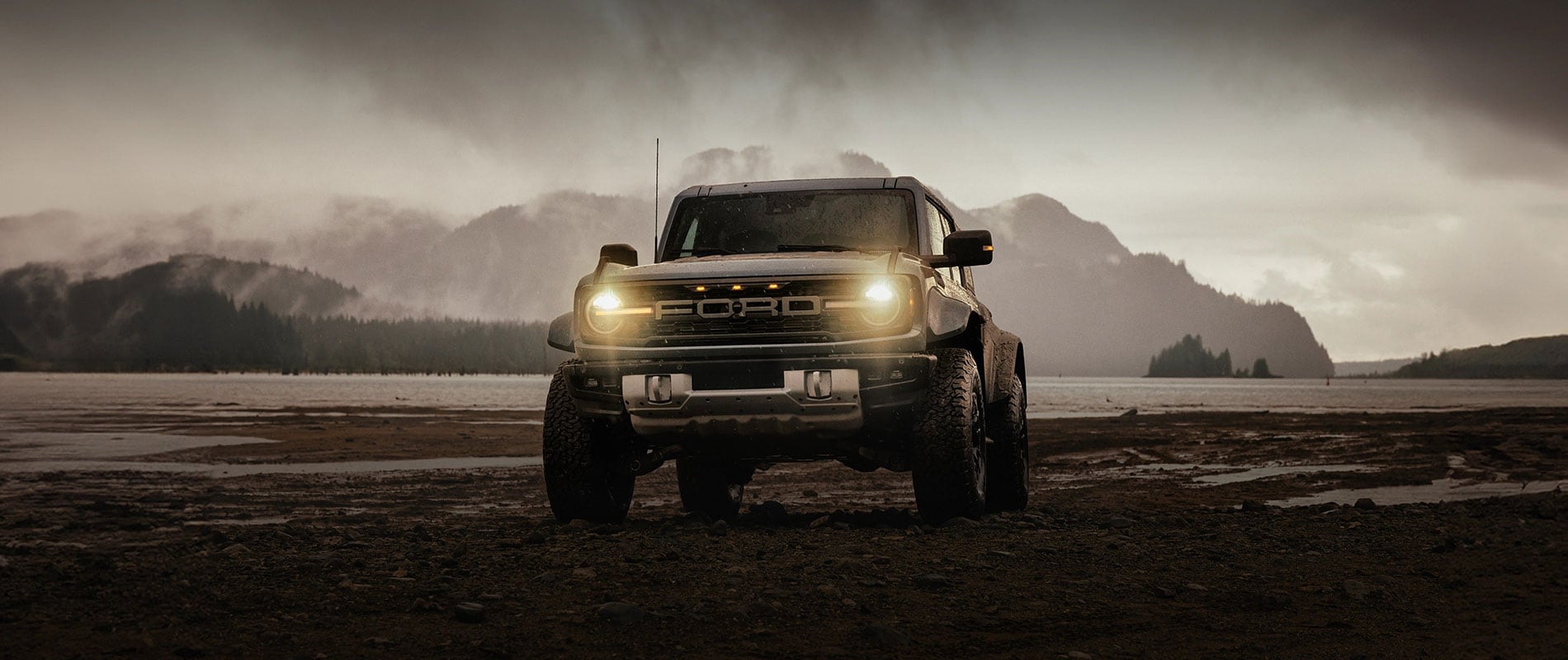 2025 Ford Bronco parked beside a lake in the rain