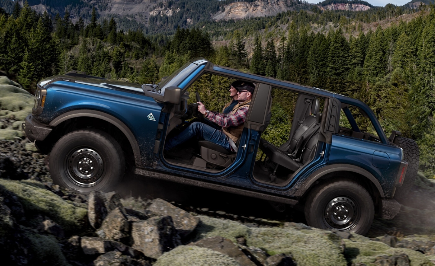 2021 Ford Bronco 4-door with all doors and roof removed driving over some large rocks