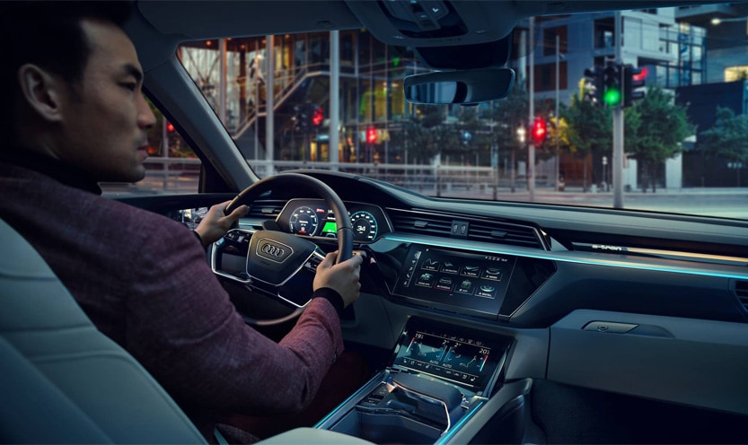 A man driving a new Audi while utilizing the innovative features inside the Virtual Cockpit.