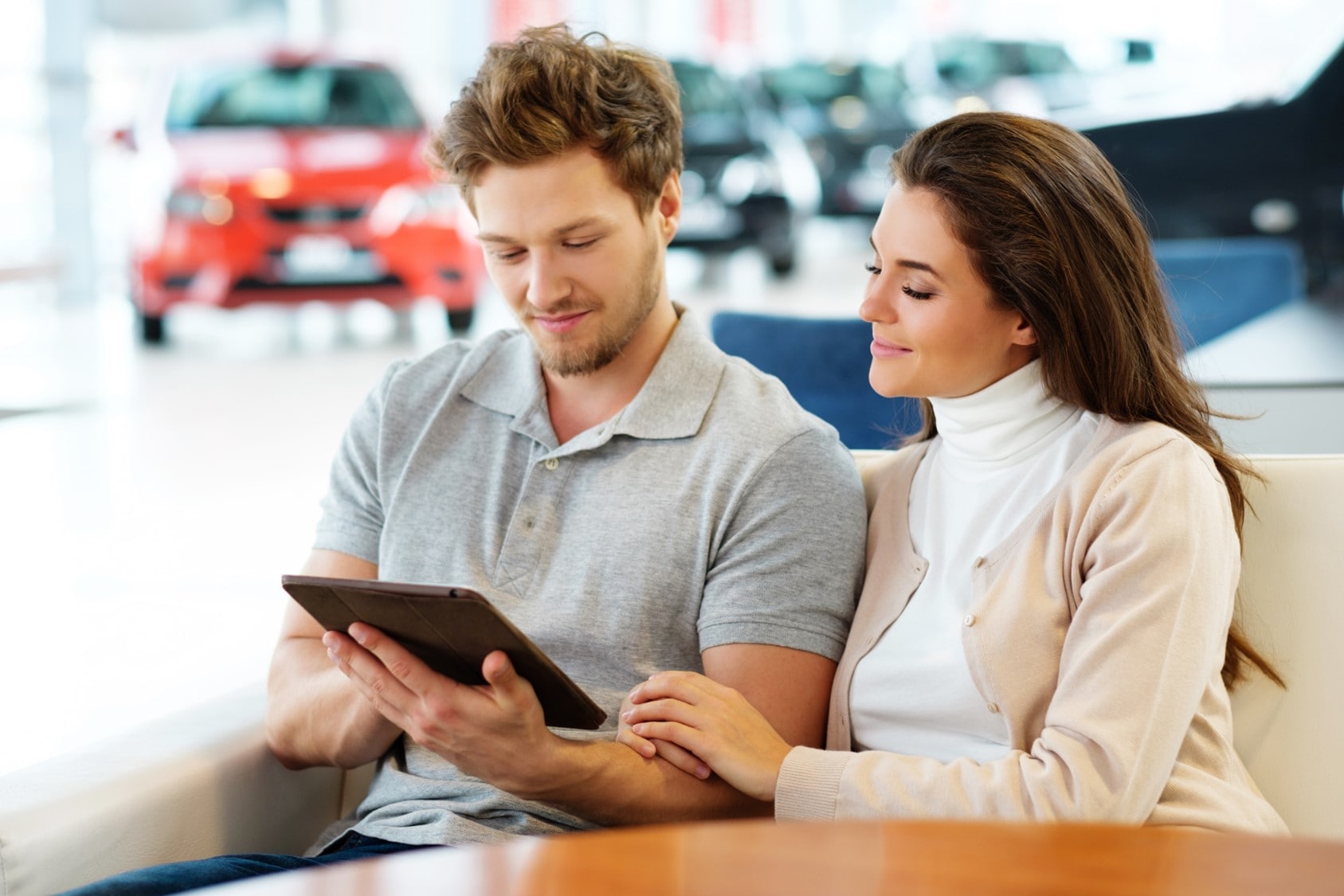 A young couple reviewing paperwork at a car dealership