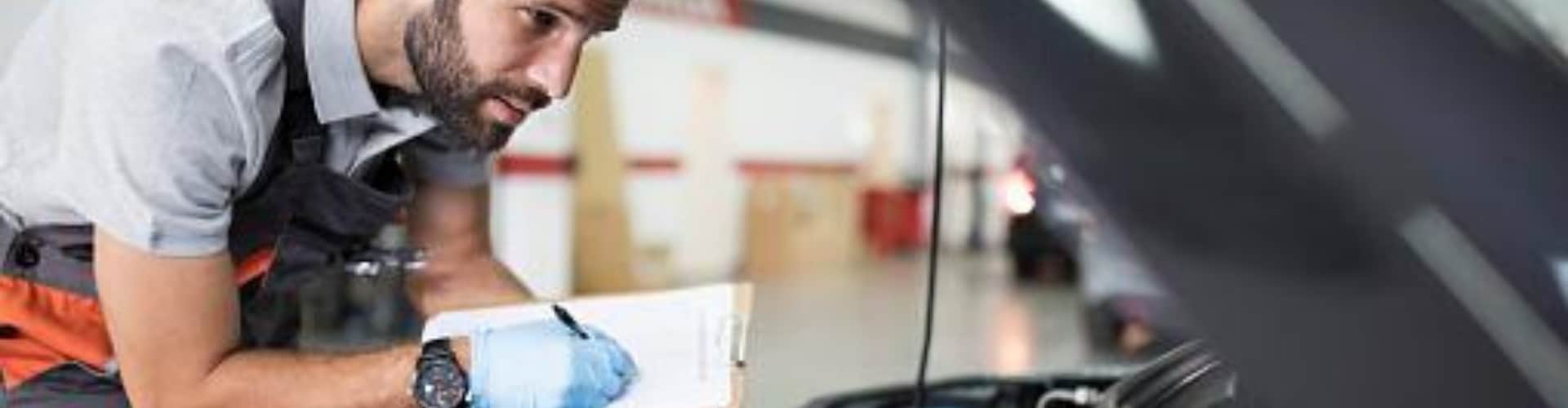 Automotive service technician performing an inspection on a used car