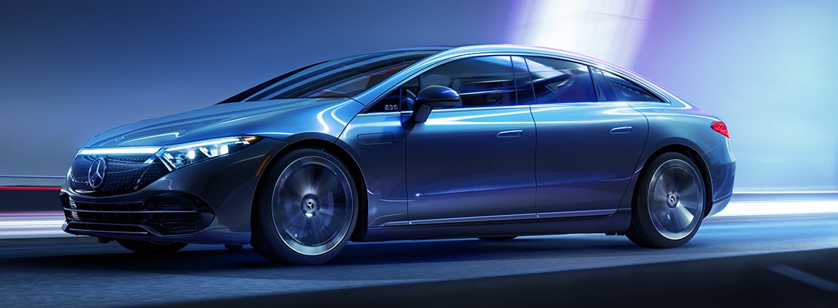 An electric blue 2022 Mercedes-Benz EQ car sits in a featureless space with various lights highlighting the finish