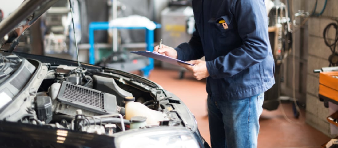 Auto mechanic performing an inspection on a used car