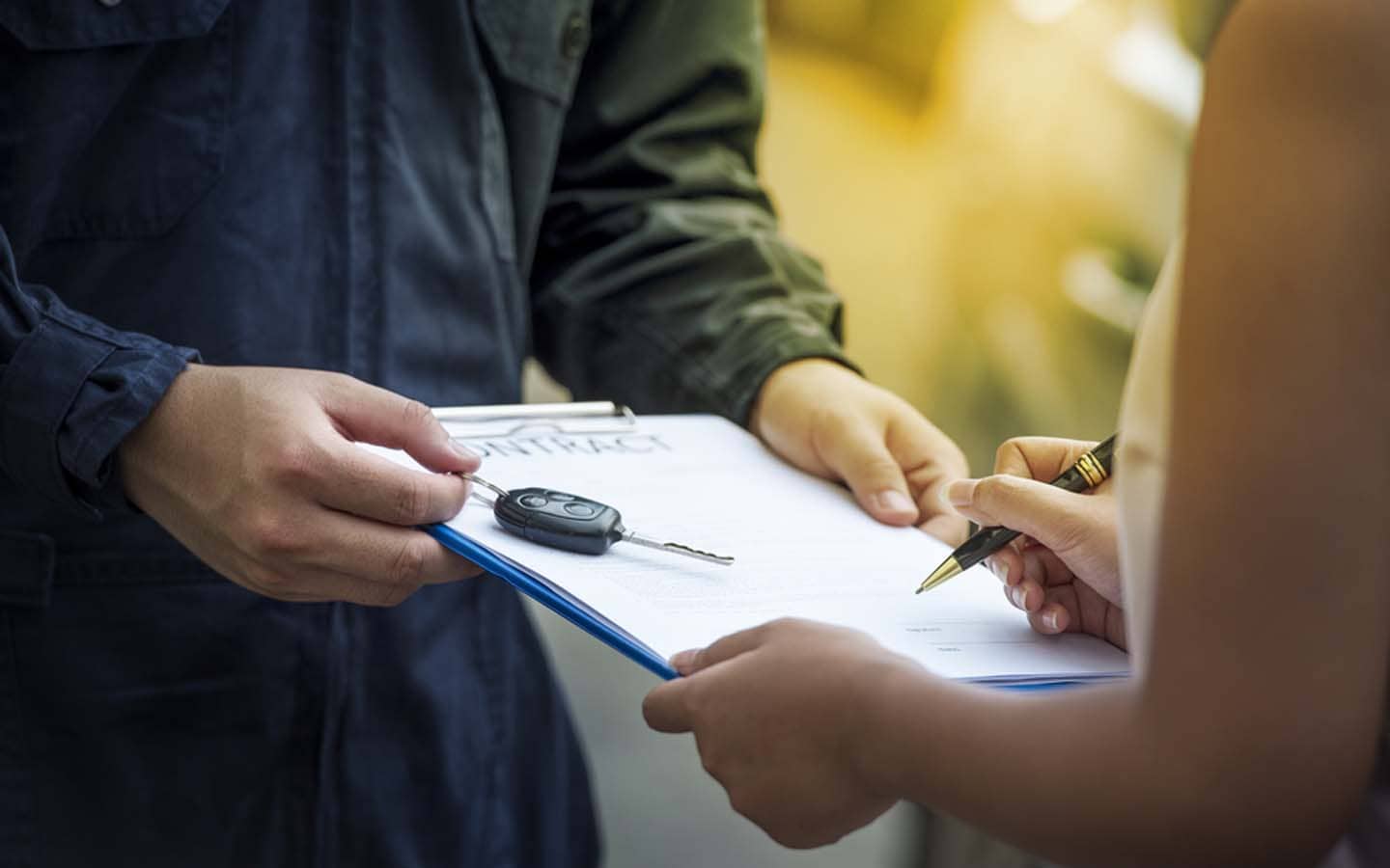 a car salesman holding out a contract for financing a car