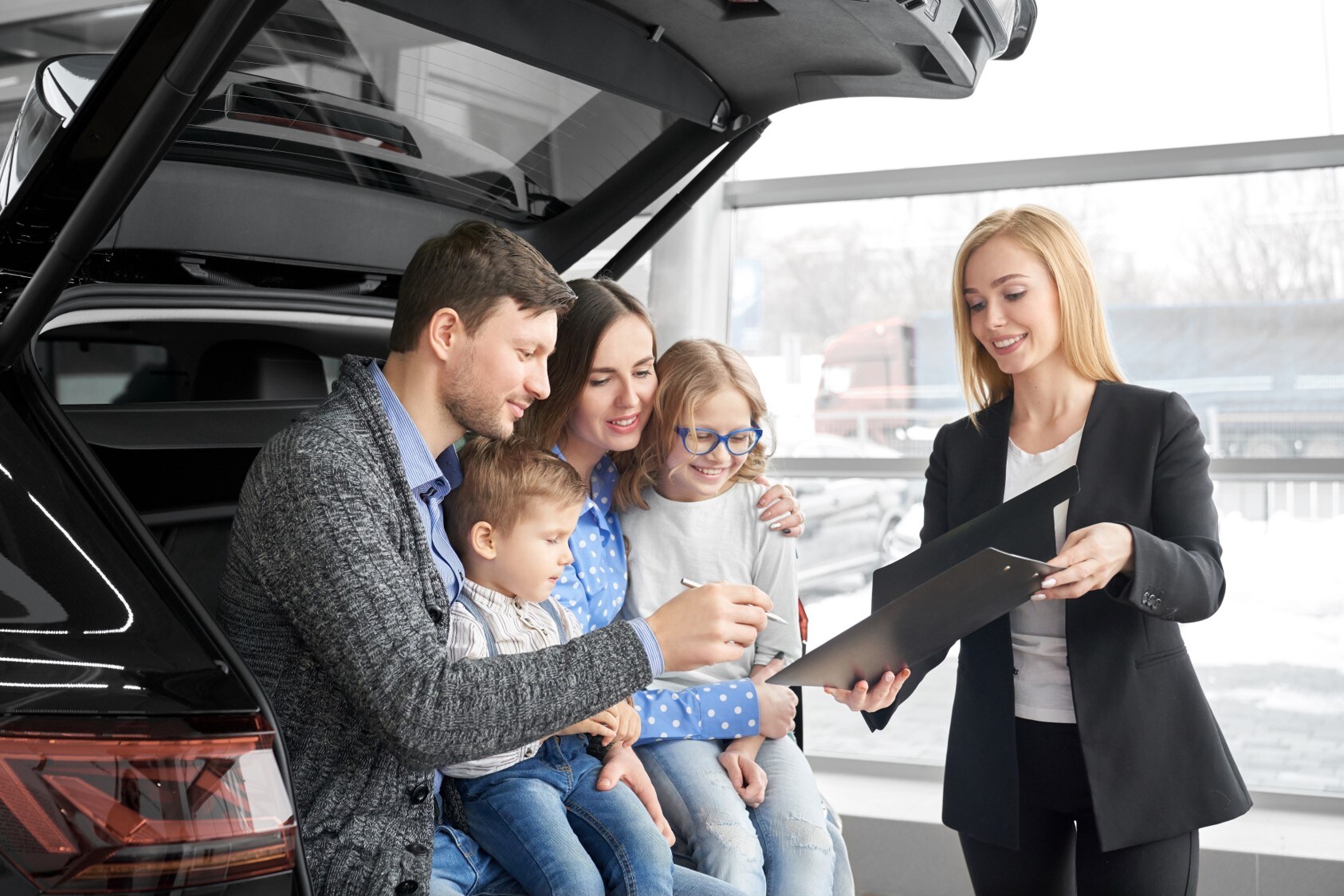 A salesperson showing a family a new car.