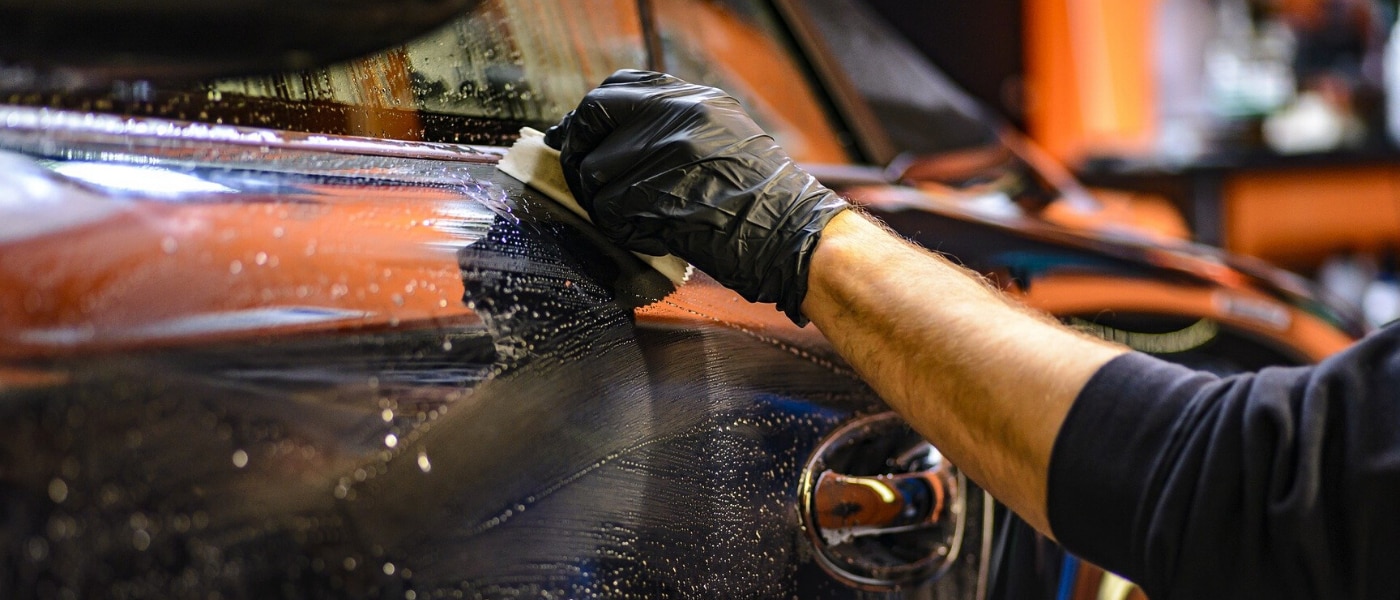 Professional car washing on display using the proper equipment and cleaning technique washing the car door of a black coupe