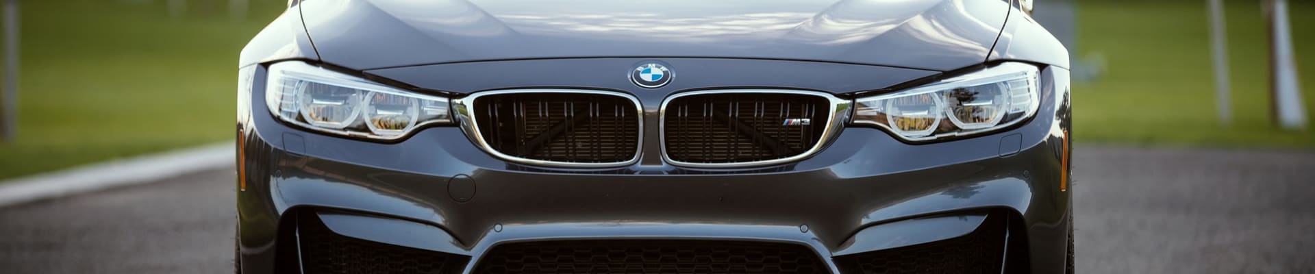 Front angle of a BMW used car in Colorado Springs zoomed in on the front grille blurry background of the road and grass