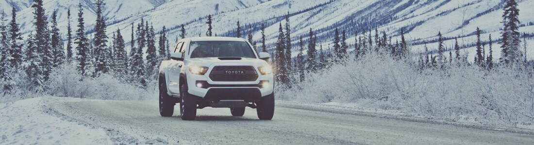 Toyota Tacoma truck driving through heavy snow in the mountains