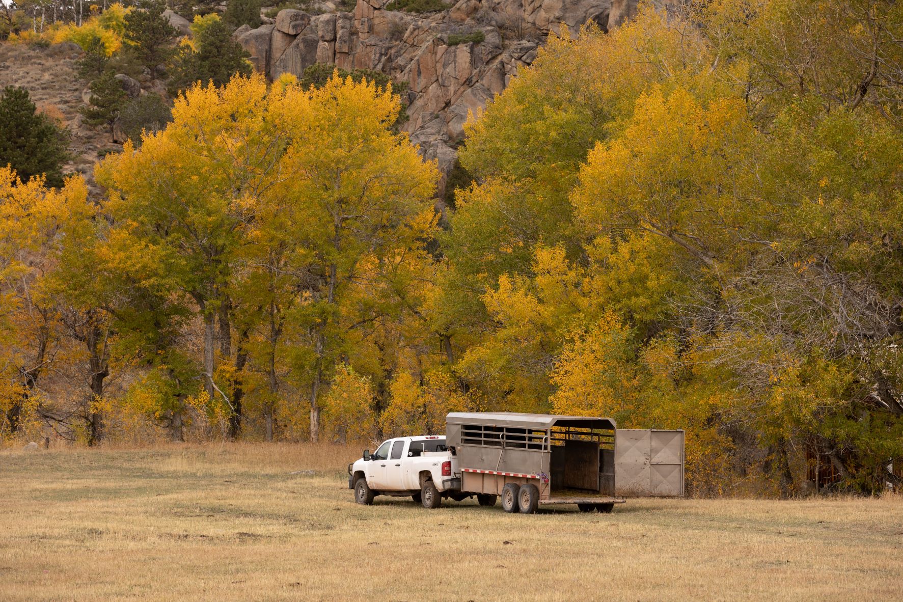 A view of a truck pulling a hose trailer through a valley in the fall.
