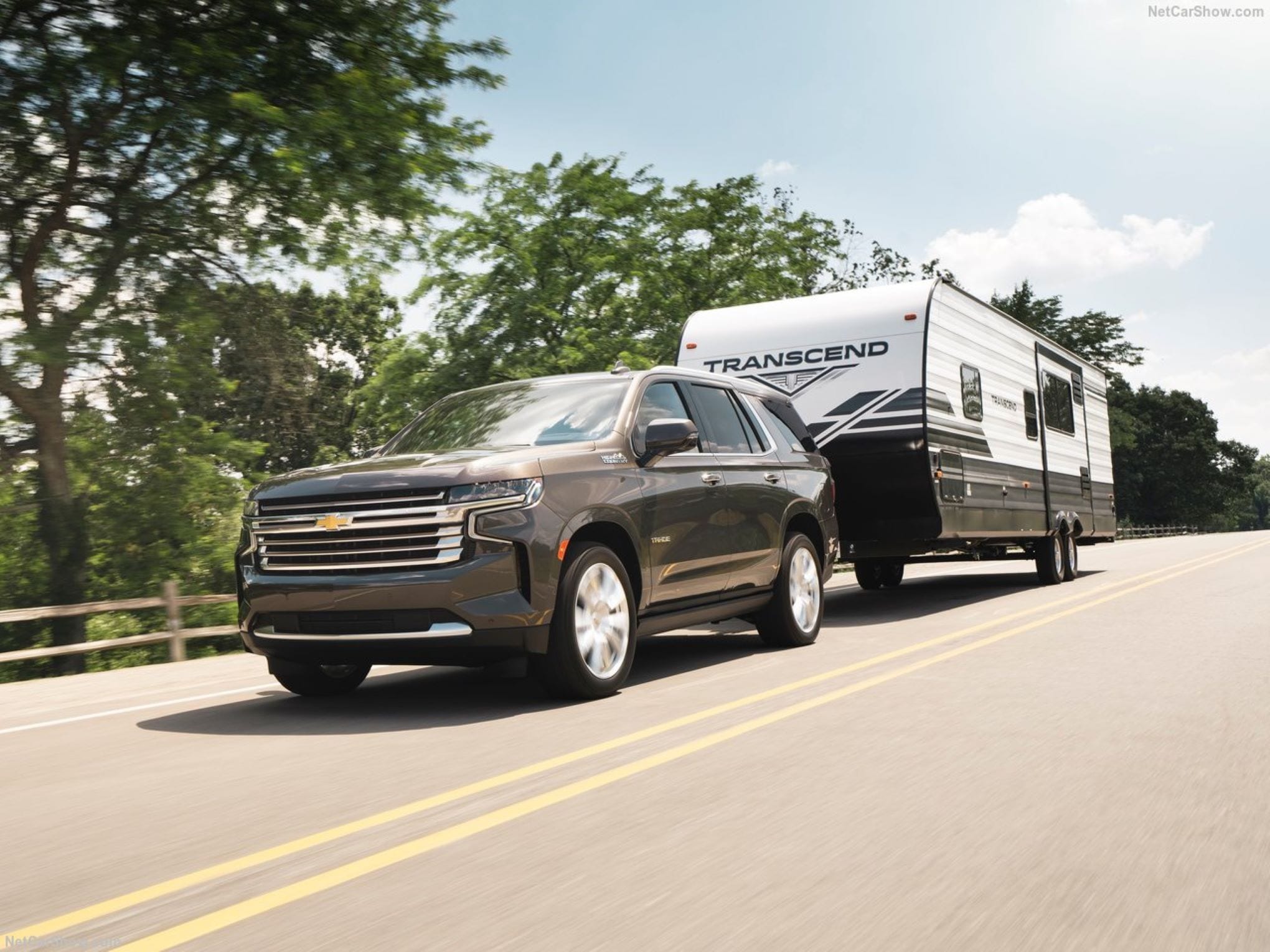 A Chevy Tahoe pulling a large camper through the mountains