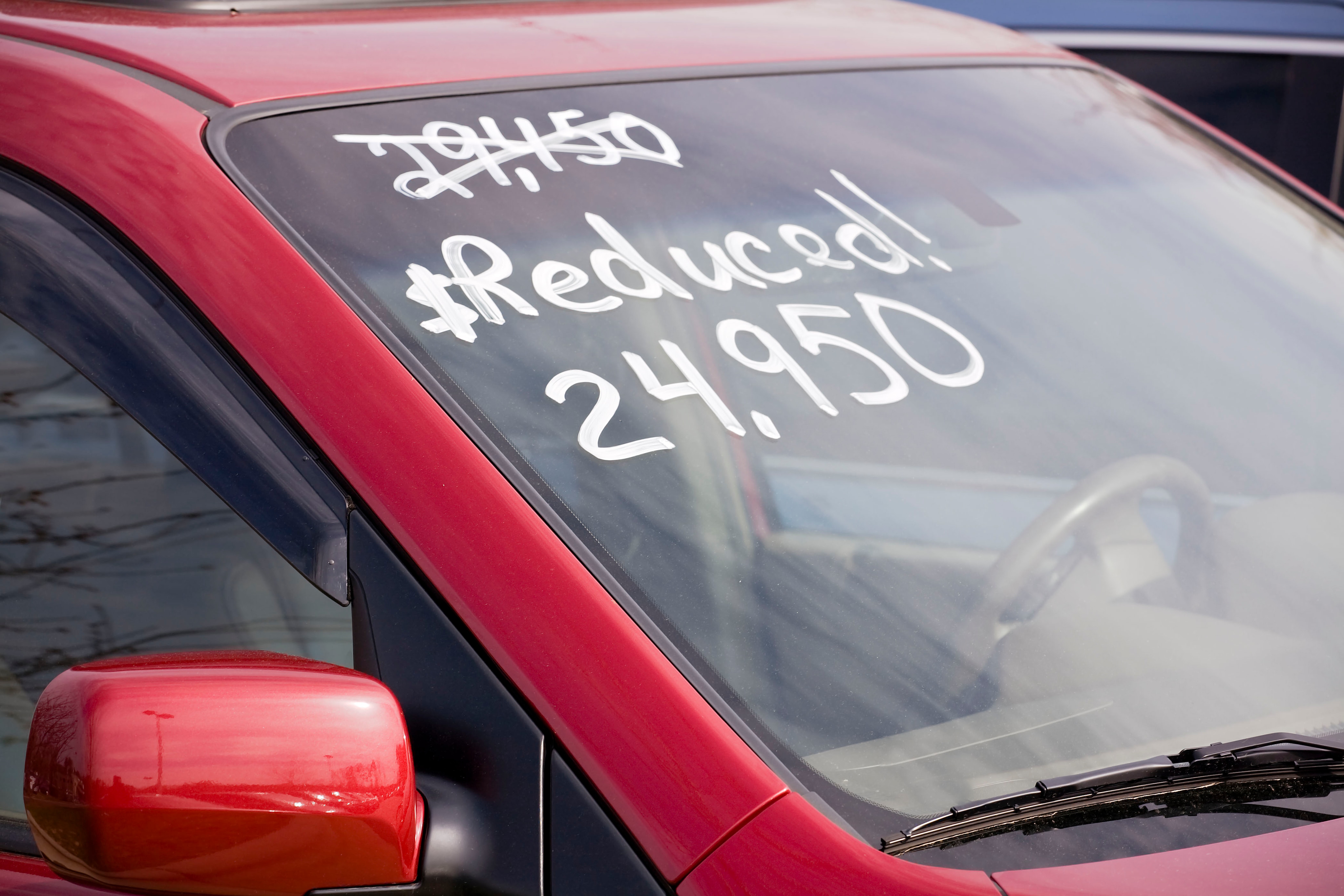 close up of the price of a used red car painted in white on the windshield