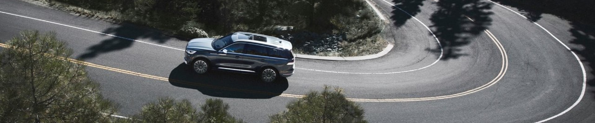 Lincoln Aviator crossover SUV driving up a curvy mountain road from an aerial view