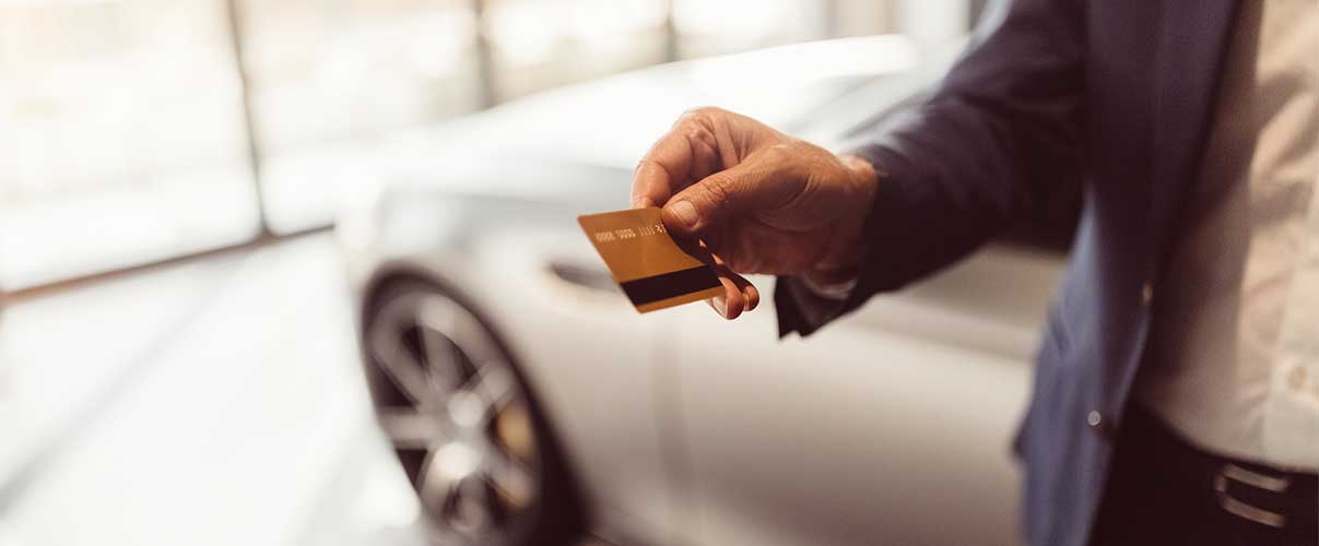 a man holding out a credit card to pay for a new Mustang