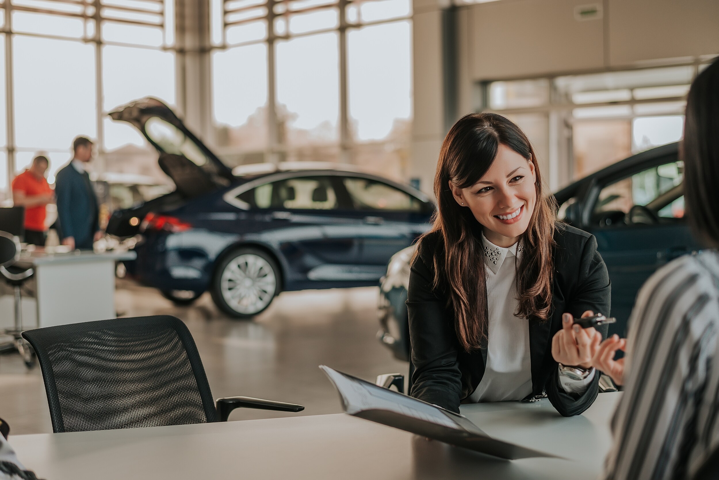 A person signing paperwork for a new car.