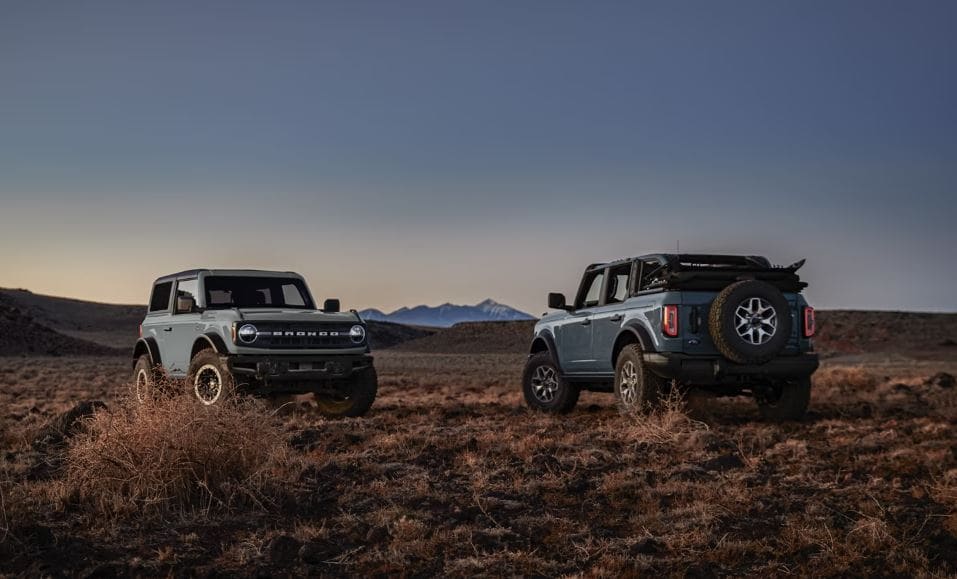 Two Ford Bronco's driving on an off road trail.