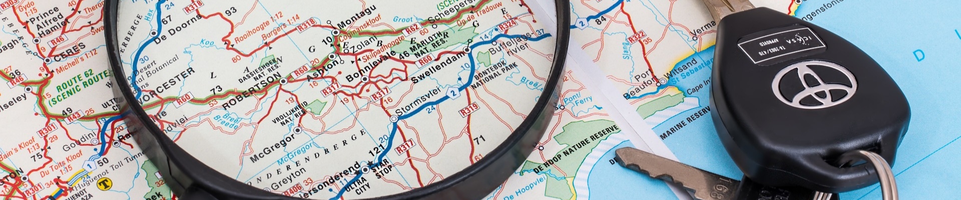 Close up view of a magnifying glass sitting on a map with a set of Toyota car keys to the right
