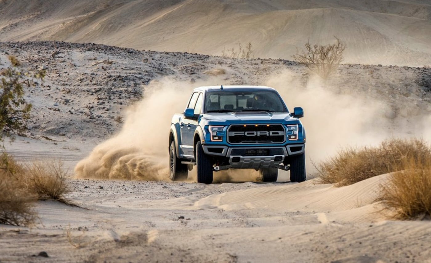 Used 2019 Ford Raptor sliding around doing donuts in deep desert sand dunes leaving a trail of dust in its wake