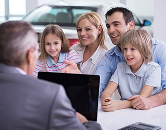 A family sitting at a Ford dealership in Denver buying a new car from Phil Long Ford