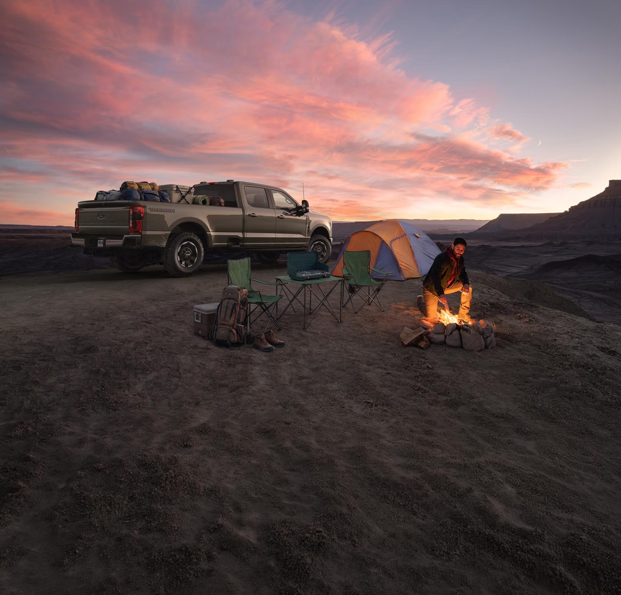 Ford Super Duty parked at a campsite with a campfire at sunset