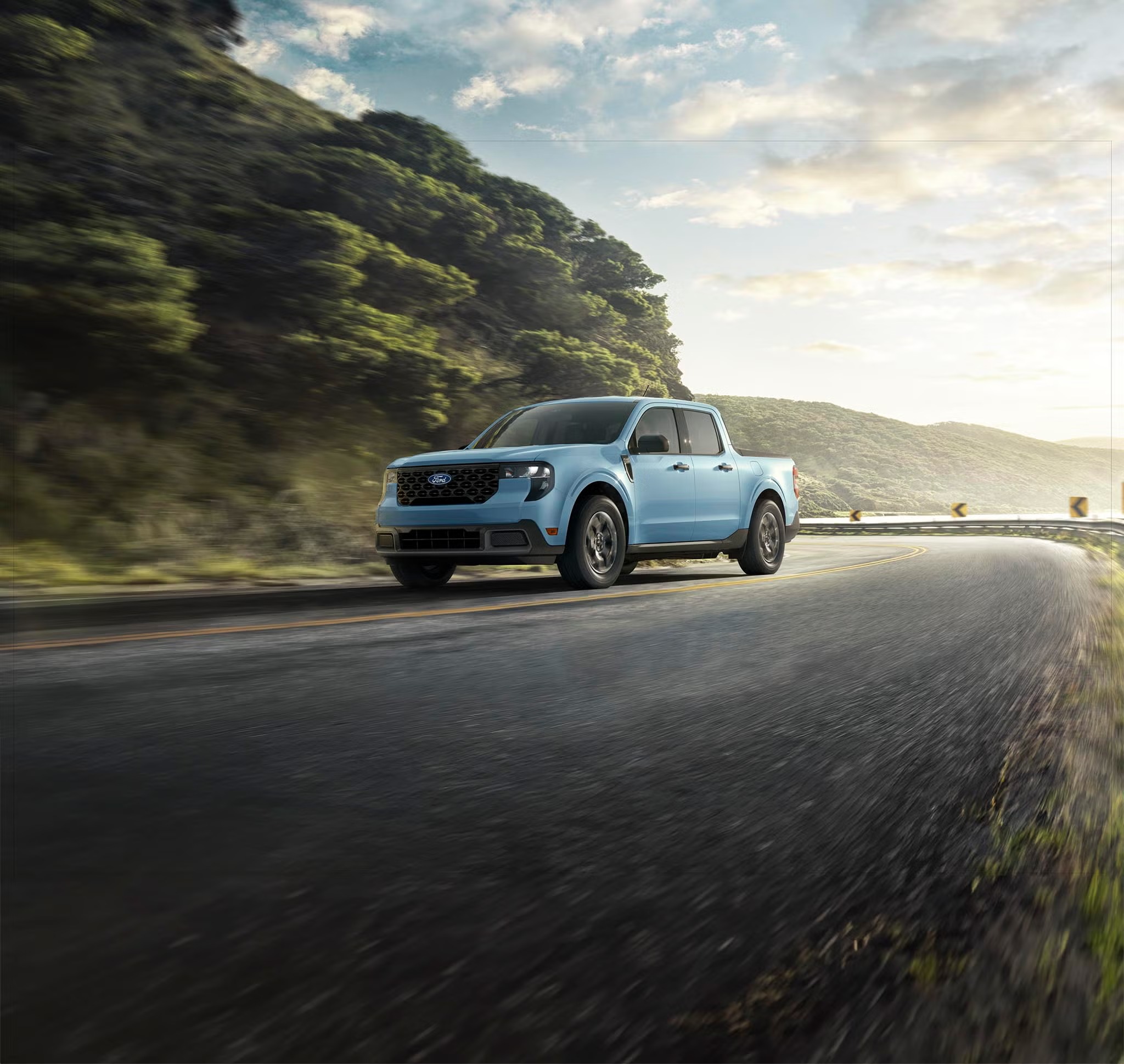 Light blue 2026 Ford Maverick driving on a winding road